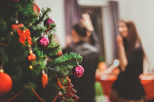 A decorated indoor Christmas tree with blurred people socialising in the background